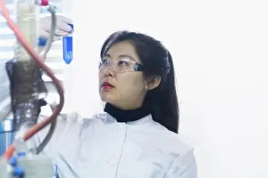 Place Of Work Prints: Young female scientist examining test tube in a laboratory
