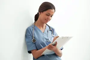 Gown Prints: Young female surgeon writing notes isolated over white background