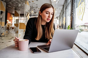 26 29 Years Old Prints: young girl in a cafe by the window working on a laptop