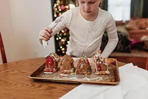 Concentrate Prints: Young girl decorates gingerbread houses at kitchen table