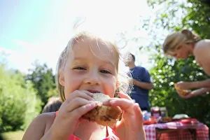 Vacationing Prints: Young girl eating sandwich at a campsite picnic