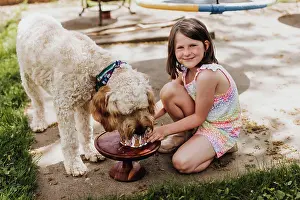 Feed Prints: Young girl holding cake while dog eats it outside in backyard