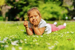 Hinreissend Prints: Young girl holding yellow Buttercup flower on meadow Young Caucasian white girl holding yellow Buttercup flower