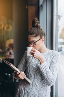 Cafe Prints: Young girl looking at tablet and smiling in cafe with big window