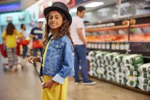 Butcher Prints: Young girl with magicians top hat and wand standing in isle of busy grocery store