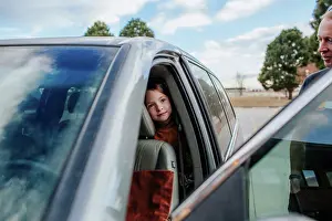 Hood Prints: Young girl peeking out from back seat of a car before a trip