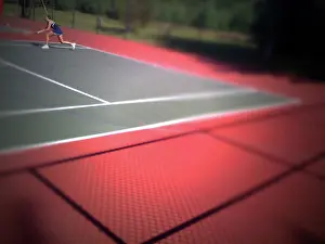 A young girl plays tennis on a bright day