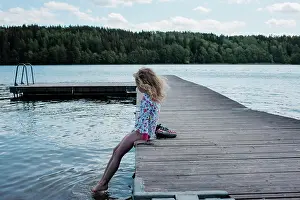 Swimming Prints: young girl sitting on a jetty looking at the water