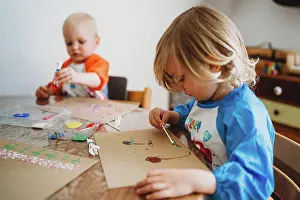 Tableware Prints: Young kids painting with lots of colorful paints at home in lockdown