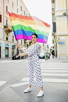 Gender Prints: Young lesbian woman standing on a street, waving rainbow flag