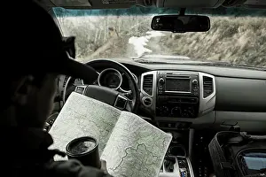 Weather Prints: Young male looking at map in truck while driving back roads of Colorad