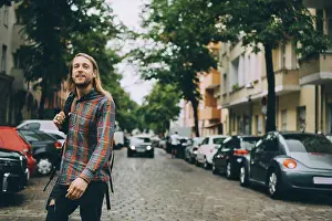 Frgbild Prints: Young man carrying backpack while walking on cobbled street amidst cars in city