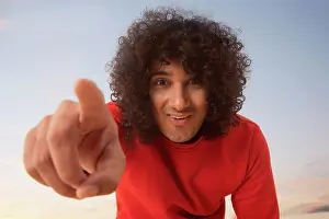 Smart Prints: A YOUNG MAN WITH CURLY HAIR HAPPILY POINTING FINGER TOWARDS CAMERA