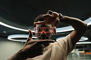 Innovation Prints: Young man with futuristic cyber glasses under modern ring lamp looking through finger frame