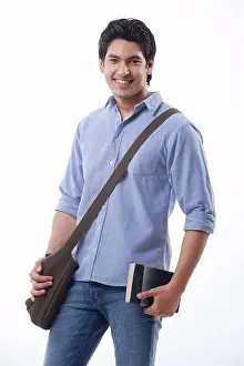 Young man holding book and shoulder bag