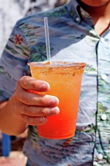Differential Prints: Young man holding michelada cocktail, mid section, close-up