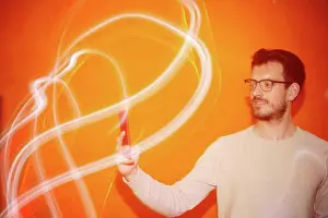 Alicante Prints: Young man looking the smartphone on a orange colored background