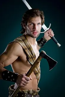 Macho Prints: Young man in warrior costume holding a sword and an axe