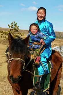 Mongolia Prints: Young Mongolian woman and child in traditional costume deel riding a horse