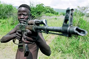 Ethiopia Prints: Young Mursi tribal man with AK-47 Kalashnikov machine gun