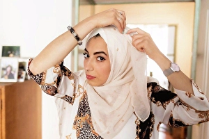 Adjusting Prints: Young muslim woman putting on hijab headscarf