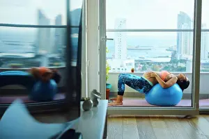 Balcony Prints: Young pregnant woman on apartment balcony lying back on exercise ball