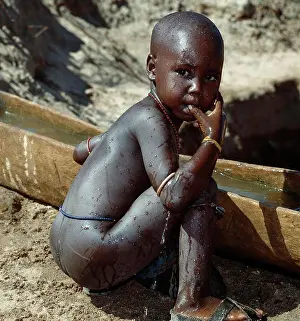 Cleaning Prints: A young Samburu boy washes himself in a wooden water trough used for the family's livestock