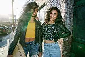 Side By Side Prints: Two young smiling women with long curly black hair standing on pavement