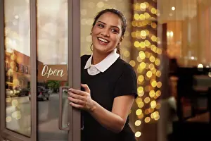 Doors Prints: A YOUNG WAITRESS HAPPILY LAUGHING WHILE OPENING DOORS TO RESTAURANT