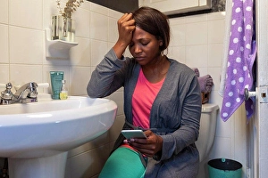 Fever Prints: Young woman in the bathroom feeling ill using Tele-medicine to communicate with a doctor
