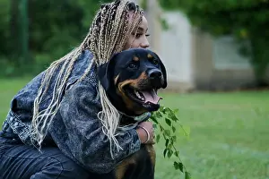 Attractive Prints: Young woman with blonde colored braided hair wearing a denim jacket and pants hugging her dog