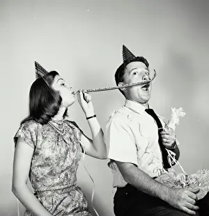 Wristwatch Prints: Young woman blowing a noisemaker near a young man's face