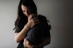 Beginnings Prints: Young woman cradling baby son in arms, low key