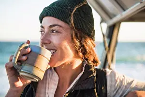 Autumnal Prints: Young woman enjoying drink in mug while beach car camping alone