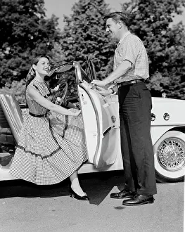 Opening Prints: Young woman getting of convertible, young man opening car door