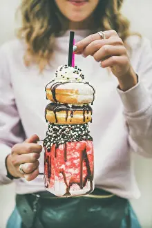 Dessert Prints: Young woman holding summer cold strawberry donut freakshake with whipped cream in mason jar in hands