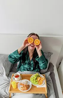 Tableware Prints: Young woman laughs and holds oranges near her eyes. Home comfort zone and wellness concept