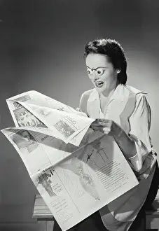 One Young Woman Only Prints: Young woman reading a newspaper with her eyes popping out
