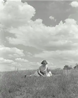 Field Prints: Young woman sitting with her baby in a field