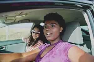 Sun Light Prints: Young woman sitting with female friend looking away while sitting in car on sunny day