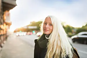 Evening Glow Prints: Young woman smiles gently on a city street at sunset