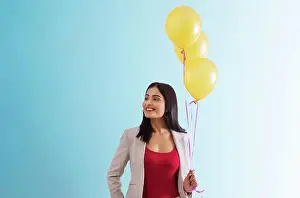 Horizontal Image Prints: Young woman standing with helium balloons in hand