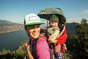 1 2 Years Old Prints: A young woman stands atop a mountain with a baby in a backpack