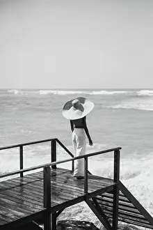 Luxury Prints: Young woman in a straw hat on the pier, ocean waves splashing