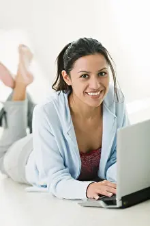 Typing Prints: Young woman using a laptop in the bedroom