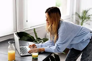 Beverage Prints: Young woman using laptop at home
