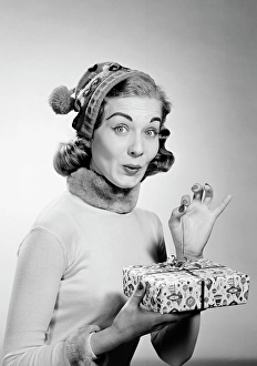 Opening Prints: Young woman wearing knit hat opening christmas gift