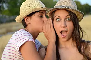 Shock Prints: Young woman whispers in friends ear