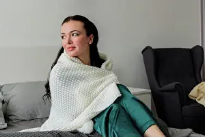 Personal Prints: Young woman is wrapped in white plaid while sitting on bed in bedroom