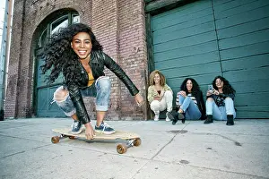 Small Group Of People Prints: Three young women with curly hair squatting in front of shutter